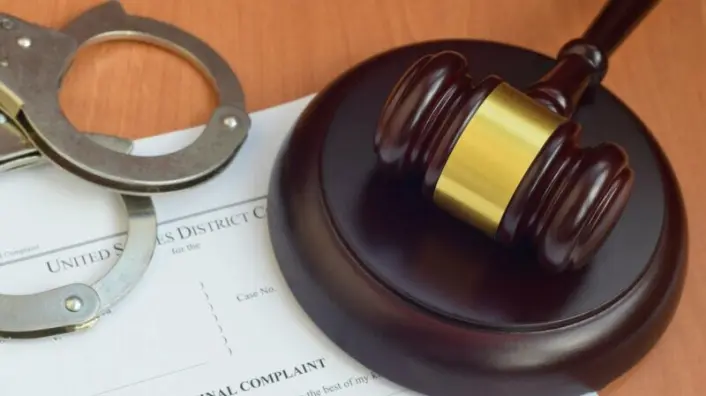 Justice mallet and criminal complaint blank document with police handcuffs