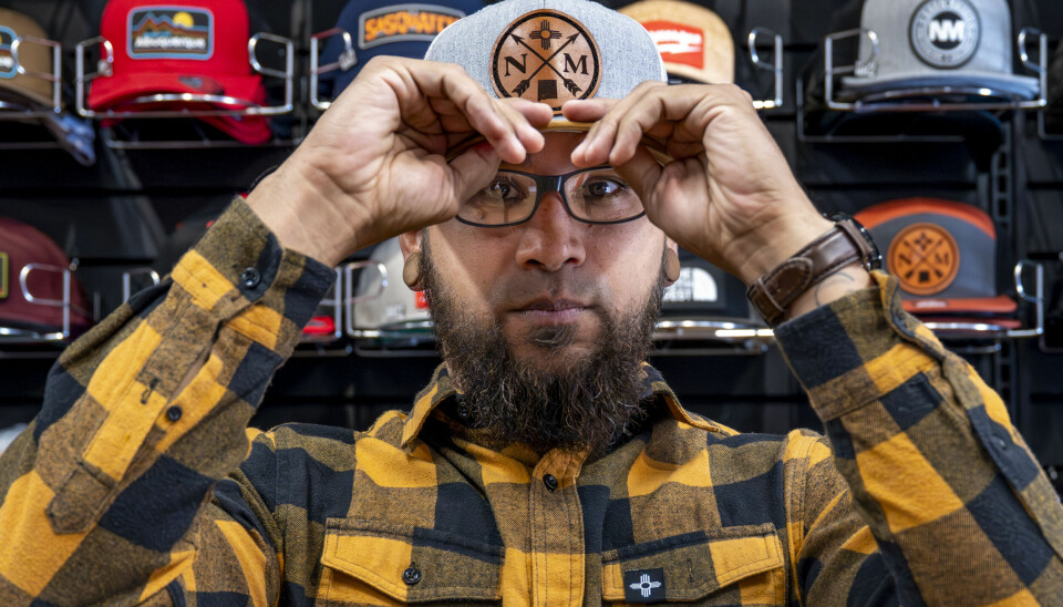 Albuquerque artist Fred Franco, owner of Albuquerque's 19Twelve Clothing Co., in his Old Town shop on Sunday. Franco got his start in graphic design while working at T-Mobile nearly a decade ago. कैसे अल्बुकर्क की 19ट्वेल्व क्लोदिंग कंपनी स्थानीय रूप से डिज़ाइन किए गए धागों के माध्यम से न्यू मैक्सिको संस्कृति को प्रदर्शित करती है