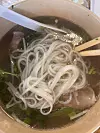 Close-up of a bowl of beef pho with rice noodles, herbs, and broth.