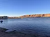 Swimmers in a calm lake bordered by desert cliffs at sunset