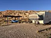 Campsite with trailer and kayak beside a rocky desert hillside at sunset