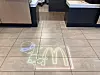 Neon-style alien and McDonald's arches graphic projected on a restaurant floor.