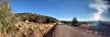 Gravel road through dry grasslands and low hills under a clear blue sky at sunset.