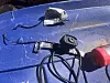 Broken rear-view camera and cut wires lying on a blue vehicle roof in sunlight