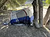 Partially collapsed tent tied between two trees at a dry campsite