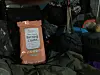 An orange package of bathing cloths lies amid bags and camping gear inside a dim van.