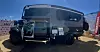 A large black Winnebago Arka expedition vehicle with oversized tires is parked outdoors at an expo.
