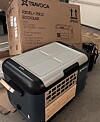 A Travoca portable electric cooler sits on a floor next to a cardboard shipping box.