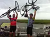 Jason Yarrington and Mark Deck hold their bikes up at the finish of the Pan Mass Challenge