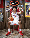 Nate Murithi, a high school senior, sits in a UNM Lobos uniform holding a basketball making a Lobos hand gesture.