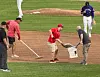 Grounds crew workers rake the infield of a baseball stadium between innings of a game.