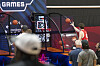 Keller Ford shoots basketballs at an arcade hoop game while several spectators stand nearby.