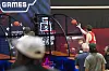 Keller Ford shoots basketballs at an arcade hoop game while several spectators stand nearby.