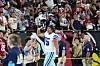 Dallas Cowboys football player Shiyazh Pete holds helmet up in air gesturing to fans in the stands in a football stadium.